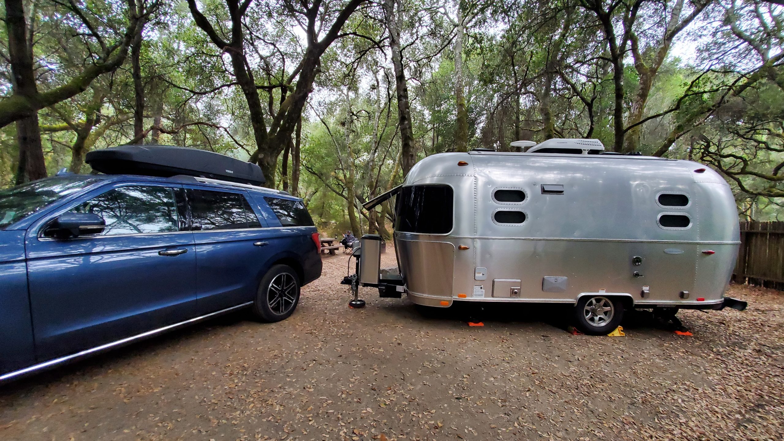 Picture of a blue Ford Expedition and a 19 foot silver Airstream in a campground.