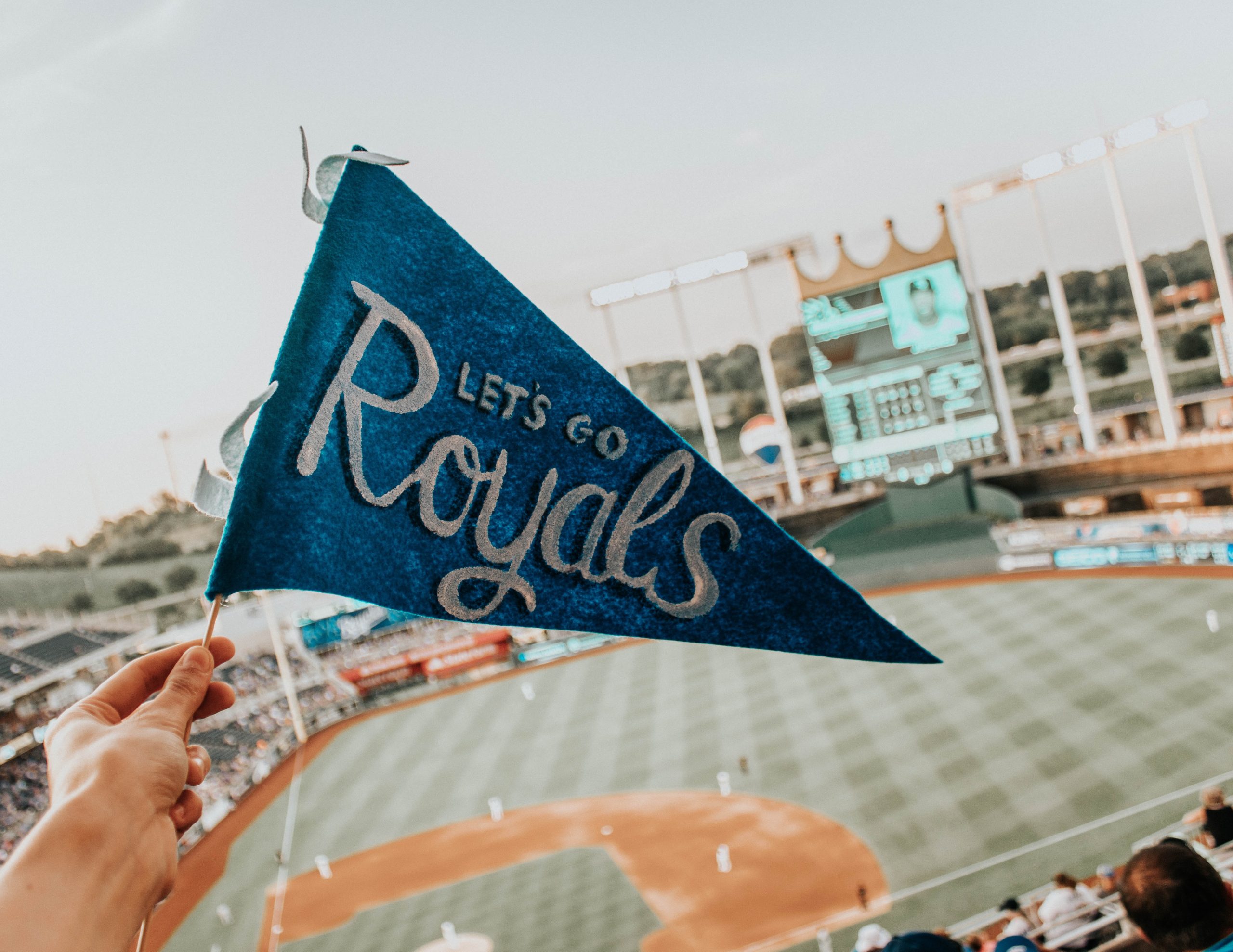 Picture of a banner that says "Let's Go Royals" with the baseball field in Kauffman Stadium in the background.