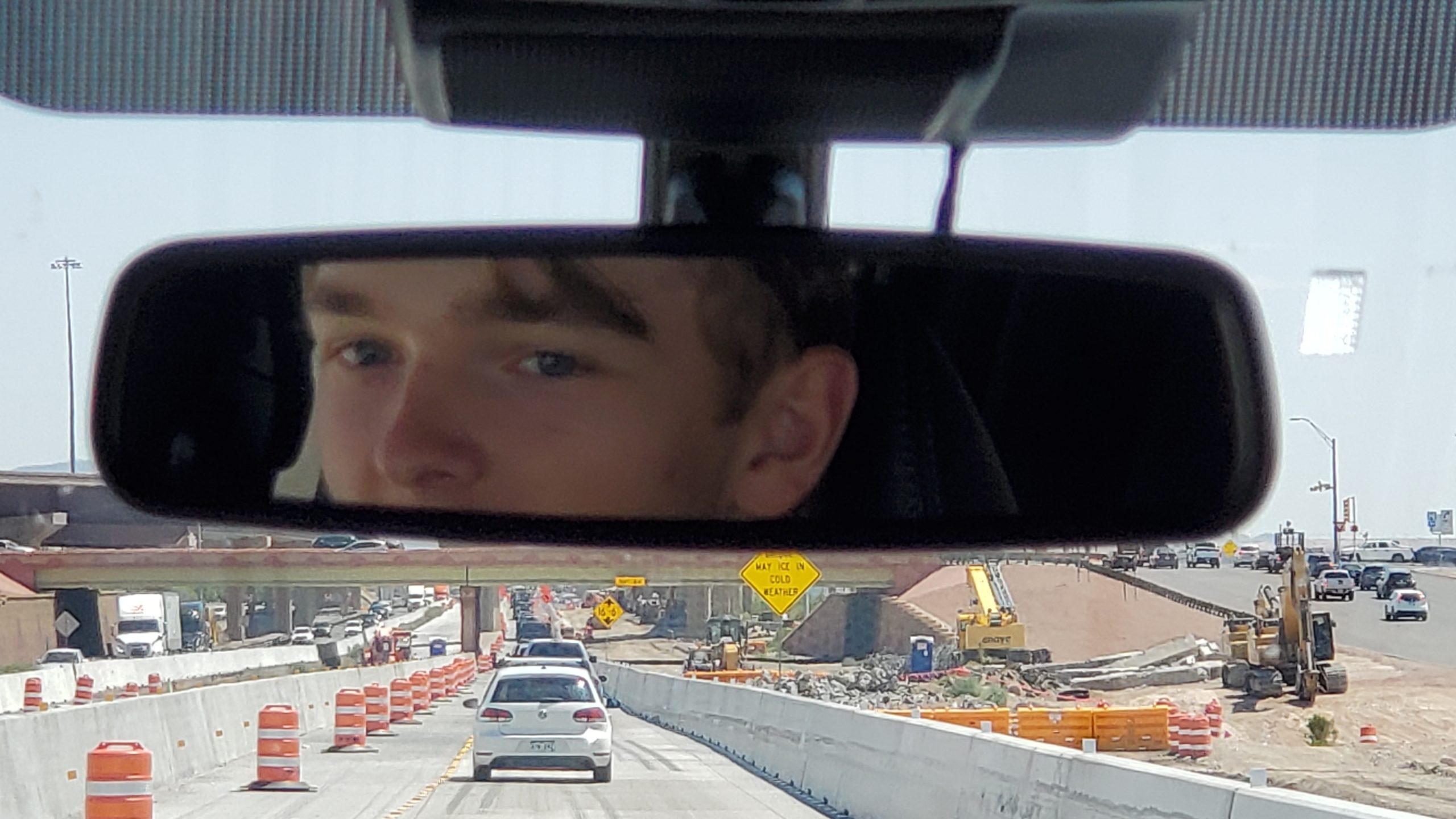 Picture of Ryan's eyes in the rear view mirror, with San Antonio traffic ahead of him.